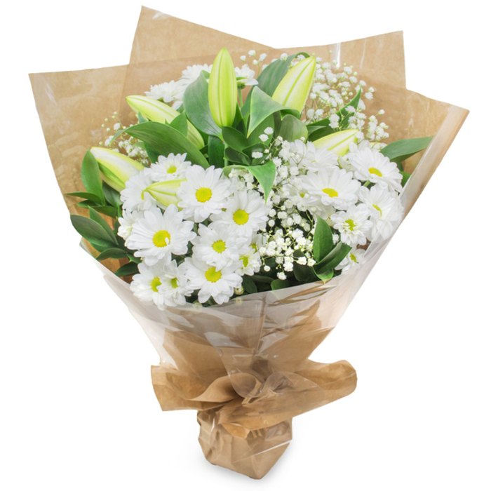 An elegantly composed bouquet presented upright against a white studio background, this arrangement celebrates the serene palette of white and green with considered craftsmanship familiar to Flowers Oxford. The central mass is made up of numerous white, daisy like chrysanthemums whose concentric layers of petals open to soft yellow centres, creating a cheerful yet gentle anchor. Scattered through the cluster are elongated lily buds in a pale green-yellow tone, some with subtle striping; their unopened forms introduce a sense of unfolding narrative and refined anticipation. Wisps of baby s breath (Gypsophila) are woven between the larger flowers, their tiny, cloud-like blossoms adding a delicate, ethereal texture that softens and harmonises the grouping. Rich dark green foliage gives the bouquet structure and contrast, the glossy leaves tucking beneath blooms to add depth and a verdant frame. The stems are hand-tied by an experienced hand and wrapped first in crinkled brown kraft paper to give an organic, tactile base, then protected with an outer layer of clear cellophane that catches the light and preserves the bouquet s freshness; the wrapping is neatly gathered and secured at the base to form a comfortable, stable stand. In soft daylight the arrangement feels calm and pure, its fragrance subtle and clean with a faint green, grassy undertone. Suitable for a wide range of occasions from quiet remembrance to joyful congratulations, it evokes the quiet charm of an Oxford morning near the Covered Market or along St Giles, and can be ordered through Flowers Oxford at flowersoxford.pro for local delivery or collection.
