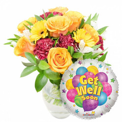 A thoughtfully composed get-well ensemble photographed on a crisp white background: a full, hand-crafted bouquet in a clear glass vase paired with a reflective silver Mylar balloon that reads Get Well Soon. At the heart of the arrangement several big, opening roses in warm orange and deep yellow form a gentle focal core, their velvety petals catching soft daylight and releasing a faint citrus-sweet scent. Bright yellow gerbera daisies punctuate that core with sunny faces, while deep burgundy carnations weave ruffled texture and shadow between blooms. Delicate white alstroemeria threads through the arrangement, lightening the palette and adding a filigree of petite blossoms. The greenery is plentiful and glossy, cradling each stem and visible through the vase's clear water, a sign of crisp conditioning and freshness. Nestled to the lower right, the round foil balloon's silvery field highlights a cheerful cluster of printed cartoon balloons in blue, purple, lime, pink and yellow-some patterned with stripes, polka dots and checks-and bold yellow-and-blue lettering sits at the centre with slight shadowing for depth. Small colorful starbursts circling the balloon's edge add a celebratory note, and a tiny Kaleidoscope mark appears at the very bottom. As a local florist, I picture this same bouquet delivered across Summertown, Jericho and the Covered Market area; Flowers Oxford prepares it with gentle care for anyone needing a bright, encouraging pick-me-up during recovery.