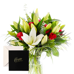 This bouquet reads as a portrait of sophistication and emotion, carefully composed to evoke both admiration and comfort. The white lilies, large and trumpet-shaped with creamy petals, rise at the heart of the arrangement like beacons in a quiet room, their presence softened by abundant green spears and curls of foliage that give the piece spatial breath. The red roses cluster throughout with quiet intensity, their velvet petals catching the light and releasing a fragrance that mingles with the lilies to form a dewy, hypnotic aroma. An abundance of unopened buds promises beauty yet to come, suggesting ongoing celebration and the promise of more to discover. The natural arrangement is caught in bright, clear light, every leaf and petal outlined with freshness. The greens provide a cooling backdrop that makes the reds feel richer and the whites more luminous, while the careful spacing lets each bloom breathe. This bouquet carries a sense of hopeful gratitude, a refined expression that can speak as easily at a hospital bedside as on a dining table in Summertown, or near a university department in central Oxford. A card marked Hero accompanies the bouquet, lending a personal note that turns appreciation into a lasting memory. Crafted by a skilled local florist, the bouquet balances classic romance with modern elegance. It is designed for durability and quiet impact, a thoughtful gift for anniversaries, milestones, or moments when a friend's courage deserves visible tribute. It is available for same-day delivery across Oxford, ensuring freshness from shop to doorstep. Whether delivered to a home near Carfax or to an office along Hythe Bridge Street, this arrangement speaks of esteem, warmth, and steadfast support.