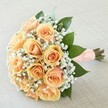 This elegant Oxford bridal bouquet brims with gentle warmth and romance, making it perfect for weddings beneath dreaming spires or intimate celebrations along the Thames. Each peach and apricot rose is carefully selected for fullness and radiant colour, their petals unfurling in perfectly balanced spirals from pale peach to a honeyed apricot centre. Soft, cloud-like baby's breath circles between the roses, adding a lacy, ethereal frame reminiscent of Oxford's timeless collegiate architecture. Deep green leaves, supple and glossy, introduce a sense of renewal, their vibrant hues echoing the lush gardens tucked behind historic Oxford walls. Every stem is gathered and wrapped in a wide, peach-toned ribbon-delicately accented by a double row of small, bright pearls-offering an inviting, textural grip. Placed diagonally against a soft beige textile backdrop, the bouquet glows under natural light, each element carefully composed to highlight both colour and form. The scent, gentle and soothing, hints at fresh roses with a breath of greenery. This floral creation, available for same-day delivery across Oxford's heart and neighbouring quarters, radiates the hope, pure joy, and delicacy that only a master local florist can achieve.