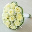 Captured from above in delicate Oxford light, this exquisite bouquet draws the eyes to its heart-a tightly woven cluster of ten to twelve creamy, almost luminescent roses, each bloom curled in a spiral that signals freshness and promise. The velvety petals glisten gently, framed and softened by a profusion of baby's breath (Gypsophila), whose diminutive white flowers lend a gossamer, cloud-like presence to the scene. Wrapped gracefully around the outer edge are broad, deep-green leaves that lend both structure and color contrast, their subtle gloss catching a touch of sunlight reminiscent of Oxford's tranquil University Parks. At the lower right, a sleek swath of white satin ribbon encases the bound stems, creating a handle both elegant and comfortable-the mark of a professional florist well-versed in the details that matter for weddings and special occasions throughout Oxford. Resting atop a softly blurred, neutral background, this bouquet's understated beauty and freshness convey purity, romance, and assured sophistication, making it a perfect companion for ceremonies, anniversaries, or any meaningful event touched by Oxford's gentle charm.