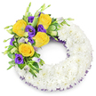 A deeply reverent funeral wreath shaped as a perfect circle, its generous ring formed from hundreds of pristine white spray chrysanthemums that read as a soft, cloud-like halo against a pale studio background. The densely packed chrysanthemums create a smooth, velvety texture you can almost feel beneath the fingertips, petals layered so evenly they suggest quiet unity and calm. Nestled on the upper left curve is a tasteful, heartfelt spray of colour: several fully opened yellow roses, warm butter-to-gold in tone, their gentle perfume faintly evoked in the arrangement's stillness, paired with rich, velvety purple lisianthus (Eustoma) whose ruffled cups lend a dignified softness. Smaller lavender-tinted lisianthus buds and slender green shoots tuck between the blooms, adding depth and a living rhythm to the composition. Fresh green foliage - glossy rounded leaves, a few variegated tips and delicate fern fronds - frames the cluster and offers cool contrast to the warm roses. A fine dark purple mesh ribbon peeks from beneath the chrysanthemum ring along both inner and outer edges, a subtle thread of colour that echoes the lisianthus and gives the design refinement without distraction. The overall impression is one of composed tenderness: pure white as a symbol of peace, yellow roses as friendship and remembrance, purple lisianthus as dignity. As a local florist describing this piece for families across Oxford - whether delivering to a service near Christ Church Meadow or leaving a tribute at a north-city chapel - I picture it set beneath soft morning light, a respectful offering that holds memories with grace and quiet beauty.