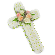 A large, traditional floral cross rests visually against a flawless white background, its shape made unmistakable by a fine outline of lime green ribbon that gently frames the flowers. The surface of the cross is completely covered in tightly packed white chrysanthemum button blooms, their small, rounded petals forming a soft, cushion-like texture from top to base. No greens or gaps interrupt this field of white, so the impression is one of immaculate stillness and purity, like a blanket of untouched snow. At the exact centre, where the horizontal arms meet the vertical stem, a small yet prominent bouquet of roses has been set into the design. These roses open generously in muted, comforting tones of creamy white, delicate peach, and soft blush pink, encircled by slender green fern fronds and wisps of pale purple or lavender filler flowers. This focal cluster creates a gentle contrast and a feeling of warmth at the heart of the cross, suggesting love held close within faith. The lighting is bright and even, highlighting the subtle shadows between each bloom and enhancing the three-dimensional nature of the tribute. The overall mood is quiet and dignified, perfectly suited to a funeral, memorial service, or graveside tribute anywhere in Oxford-from a church near Iffley Road to a chapel in Botley. It looks like a piece a local florist would prepare with great care, intended to comfort grieving family and friends while honouring the memory of someone who has passed with grace and respect.